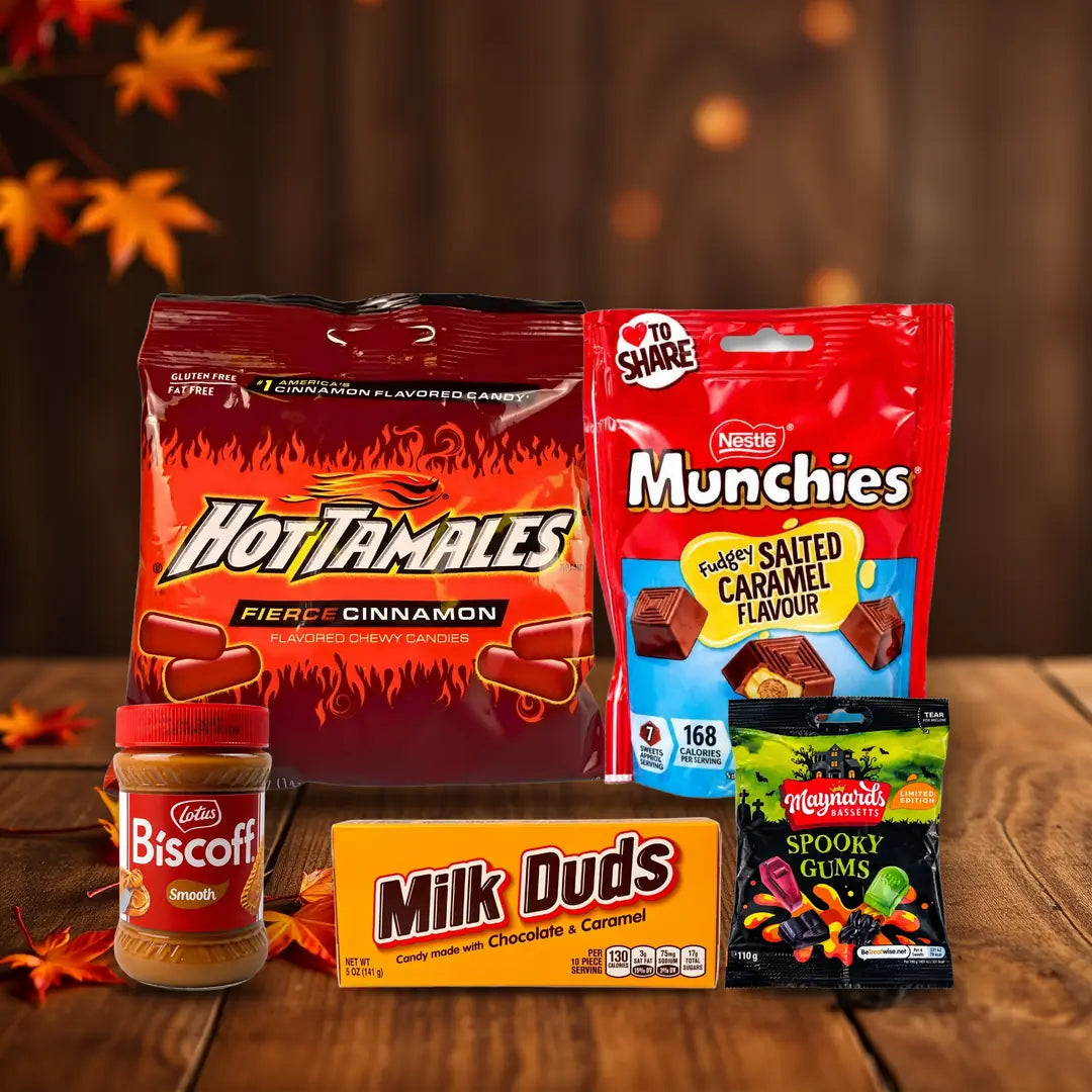 Herbst-Snacks bei MiMa's: Hot Tamales, Kit Kat Ghost Toast, Munchies, Lotus Biscoff, Milk Duds und Spooky Gums auf herbstlichem Holztisch
